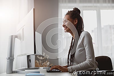 Portrait of cheerful smiled young woman coder working from home browsing on computer Stock Photo