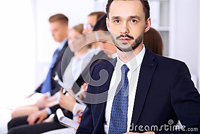 Portrait of cheerful smiling businessman against a group of people at meeting. Stock Photo