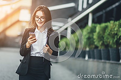 Portrait of cheerful young woman talking on smartphone and laughing outdoors. Happy beautiful caucasian woman using Stock Photo