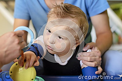 Portrait of a child with cerebral palsy on physiotherapy in a children therapy center. Boy with disability has therapy by doing Stock Photo