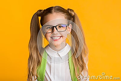 Portrait Of Clever Schoolgirl Smiling At Camera Over Yellow Background Stock Photo