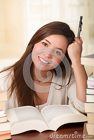 Portrait of clever student with open book reading it in college library holding a pen Stock Photo