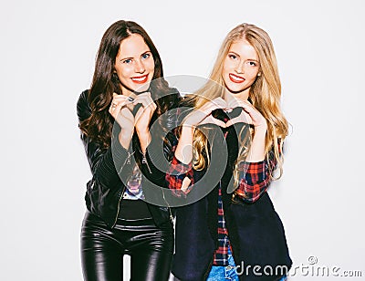 Portrait close up happy smiling two young womans showing heart sign gesture with hands nex to white background. Positive human emo Stock Photo