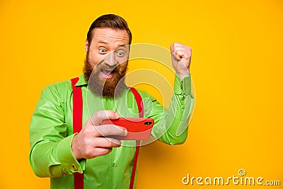 Portrait of competitive cheerful ecstatic man use smartphone play video online game win race scream yeah raise fists Stock Photo