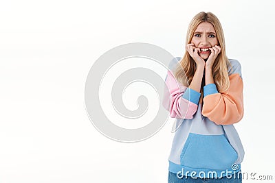 Portrait of concerned, scared and insecure young blonde woman biting nails anxious and worried, frowning, trembling fear Stock Photo