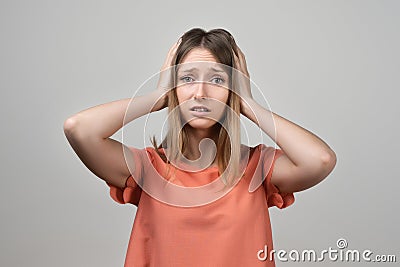 Portrait of concerned, worried and anxious blond girl, grab head and panicking, staring alarmed, feel scared and nervous Stock Photo