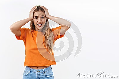 Portrait of concerned, worried and anxious insecure blonde girl, grab head and panicking, staring alarmed, feel scared Stock Photo