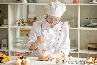 Portrait of confectioner topping a cupcake with cream Stock Photo