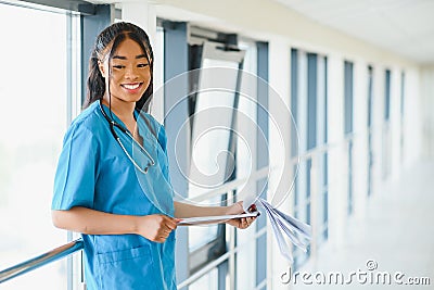 Portrait confident African American female doctor medical professional writing patient notes isolated on hospital clinic hallway Stock Photo