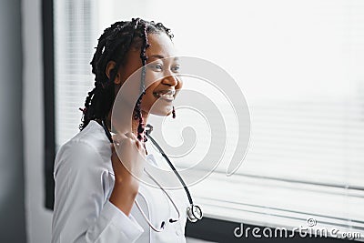 Portrait confident African female doctor medical professional writing patient notes isolated on hospital clinic hallway Stock Photo