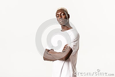 Portrait of confident assertive african-american guy with blond hair, cross arms chest and looking sassy, standing white Stock Photo