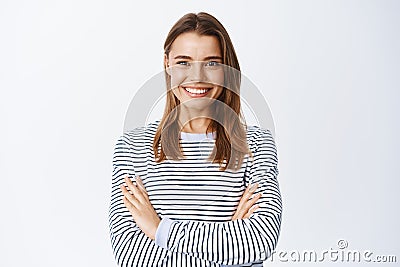 Portrait of confident blond woman with determined expression, cross arms on chest and smiling white teeth at camera Stock Photo