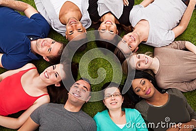 Portrait of confident college students lying on grass Stock Photo