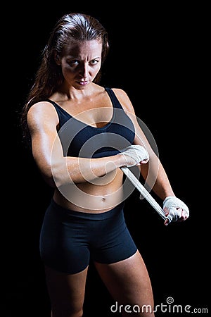 Portrait of confident female fighter tying bandage on hand Stock Photo