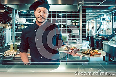 Portrait of a confident master chef holding two plates with tasty food Stock Photo