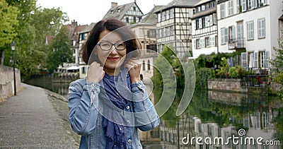 Portrait of confident Mature Caucasian woman in glasses looking serious wearing scarf in ancient European city Stock Photo