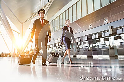 Portrait of confident pilot with stewardess walking in airport Stock Photo
