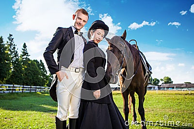 Portrait of confident well-dressed couple standing with horse on field Stock Photo