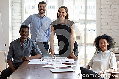 Joyful millennial diverse professionals gathered near table. Stock Photo