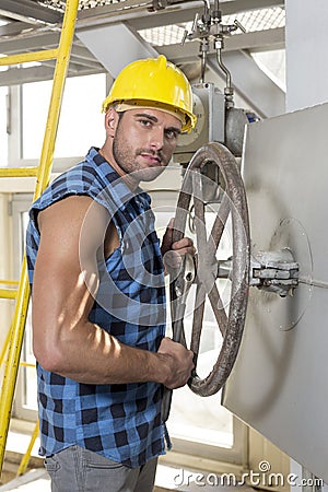 Portrait of confident young worker fixing industrial valve Stock Photo