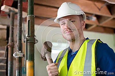 Portrait Of Construction Worker With Sledgehammer Demolishing Wall In Renovated House Stock Photo