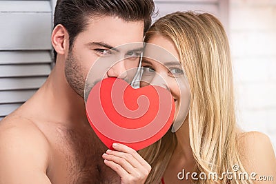 Couple covering faces with red paper heart Stock Photo