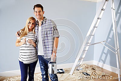 Portrait Of Couple Decorating Nursery For New Baby Stock Photo