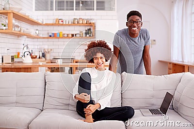 Portrait Of Couple Relaxing On Sofa At Home Looking At Laptop Together Stock Photo