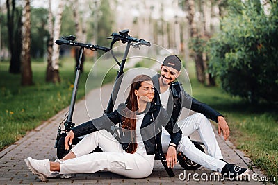 Portrait of a couple sitting near electric scooters, enjoying time in nature together, Two lovers on electric scooters.People on Stock Photo