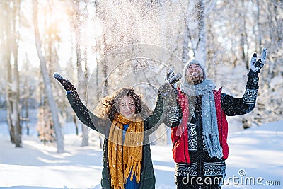 Portrait of couple standing outdoors in snow in winter forest, throwing snow. Stock Photo