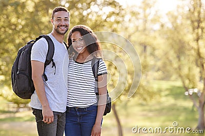 Portrait Of Couple Wearing Backpacks Hiking In Park Together Stock Photo