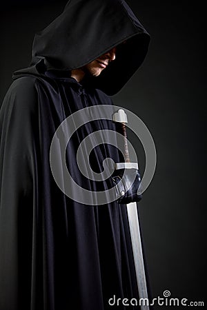 Portrait of a courageous warrior wanderer in a black cloak and sword in hand. Stock Photo