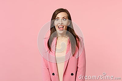 Portrait of crazy funny loony young woman in jacket with beveled eyes showing tongue isolated on pastel pink wall Stock Photo