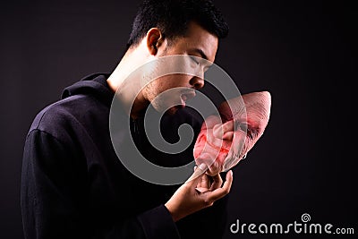 Portrait of crazy young Asian man with hoodie holding horror mask Stock Photo