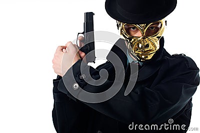 portrait of criminal in golden mask hat and black coat with gun in hands looking at camera Stock Photo