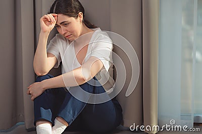 Portrait of a crying woman, clutching her head and sitting on the floor. Copy space. The concept of domestic violence and day of Stock Photo