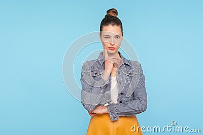 Portrait of cunning smart fashionably dressed woman with hair bun looking at camera and thinking over revenge Stock Photo