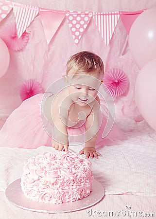 Portrait of cute adorable Caucasian baby girl with blue eyes in pink tutu skirt celebrating her first birthday with gourmet cake Stock Photo