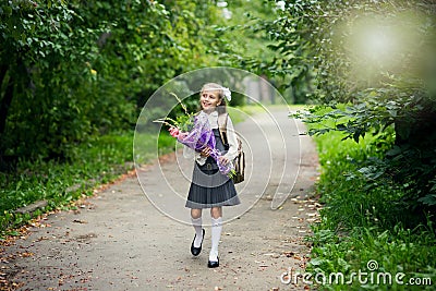 Portrait of cute adorable little caucasian school girl wearing uniform and flowers bouquet going back to school Stock Photo