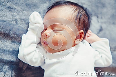 Portrait of cute adorable sleeping Asian Chinese mixed race newborn baby girl boy lying on bed in bedroom. Stock Photo