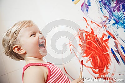 Portrait of cute adorable white Caucasian little boy girl playing and painting with paints on wall in bathroom Stock Photo