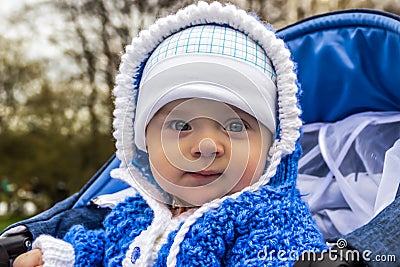 Portrait of cute baby with angel eyes sitting in stroller. Age of the baby is 6 months. Stock Photo