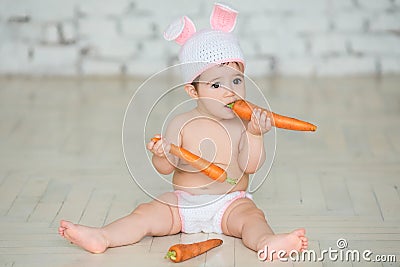 Portrait of a cute baby dressed in Easter bunny ears sitting and Stock Photo