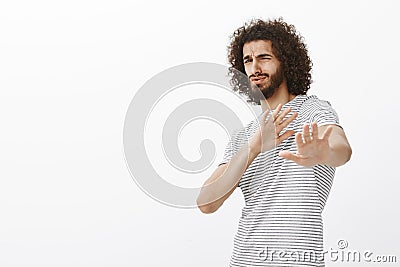 Portrait of cute bearded digusted guy in trendy outfit, bending backwards and pulling palms towards camera, defending Stock Photo