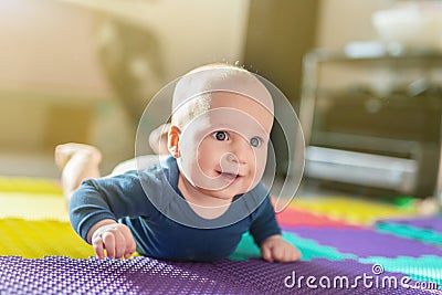 Portrait of cute caucasian baby boy crawling on soft playing mat indoors. Adorable child having fun making making first steps on f Stock Photo