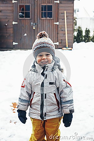 Portrait of a cute contented todler boy in winter clothes outdoors in the snow. Winter time, winter fun, happy childhood. Vertical Stock Photo