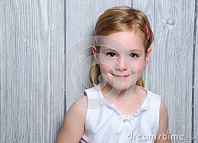 Portrait of a cute four-year smiling blonde girl in white dress and colorful barrettes in her hair Stock Photo