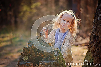 Portrait of cute happy child girl playing with tree in early spring forest Stock Photo