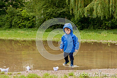 Portrait of cute kid boy playing with handmade ship. kindergarten boy sailing a toy boat by the waters` edge in the park Stock Photo