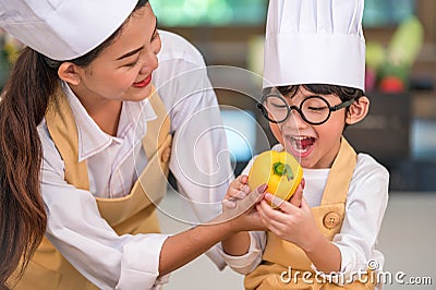 Portrait cute little Asian happy boy chef interested in cooking with mother funny in home kitchen. People lifestyles and Family. Stock Photo